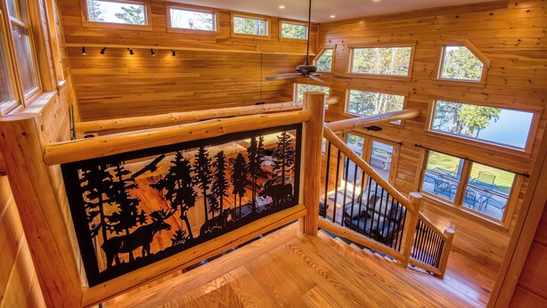 A wooden interior with a staircase, a ceiling fan, and multiple windows. - Dodge Lodge | Private Waterfront on Dodge Pond, Newly Renovated, Near Downtown Rangeley (Rangeley)
