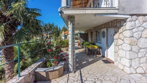 Un bâtiment en pierre doté d’un balcon, d’un espace extérieur aménagé pour s’asseoir et d’un jardin fleuri.