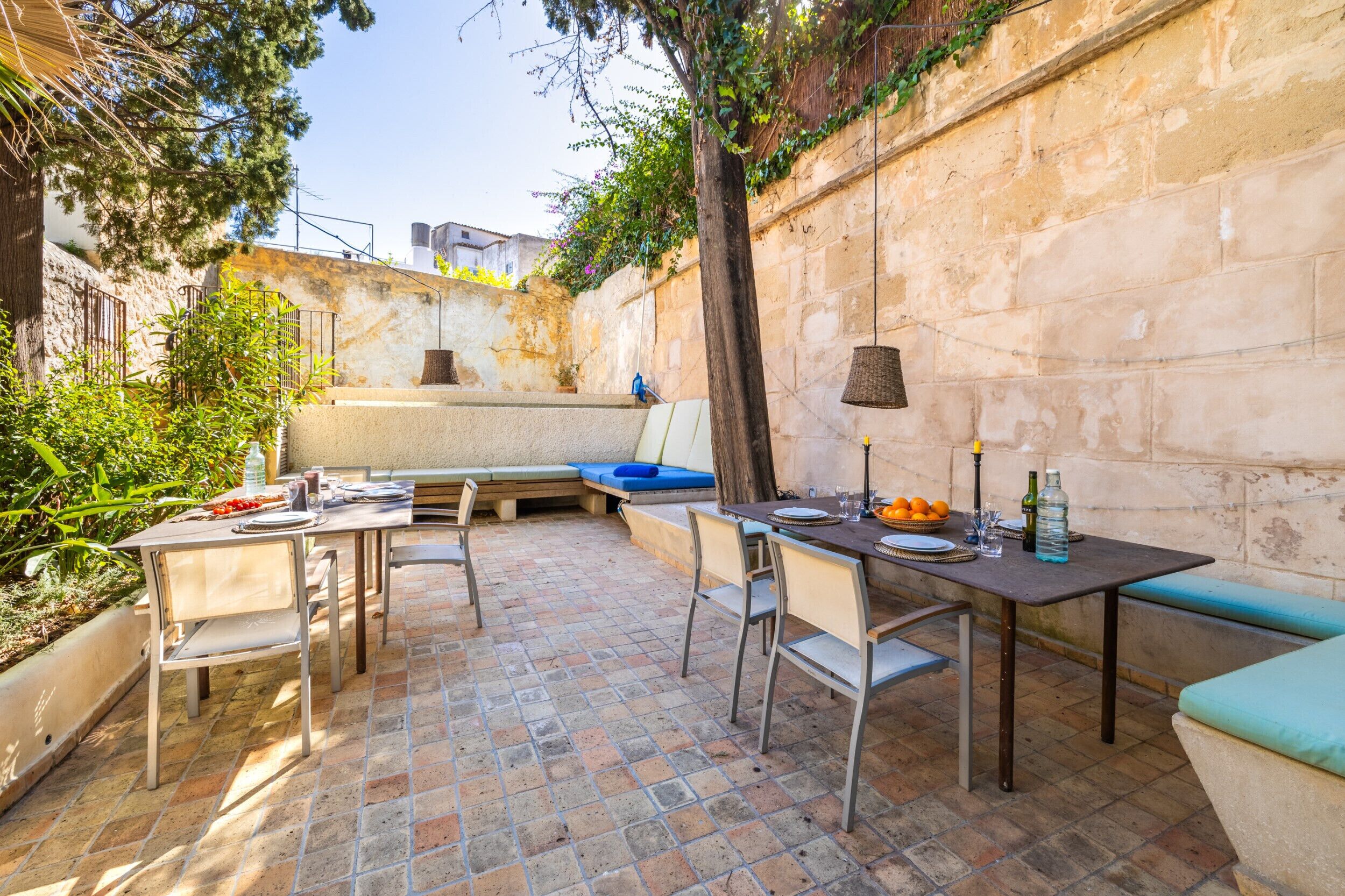 Un patio al aire libre con una mesa dispuesta para comer, rodeado de sillas y un banco.