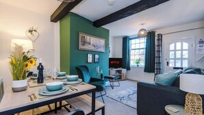 Una sala de estar moderna con comedor, pared de acento verde y vistas al exterior.