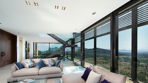 A modern living room with a glass coffee table, beige sofas, and a view of a mountainous landscape. - Casa Liebre by Balearic Villas (Pollensa)