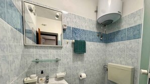 Een badkamer met een wastafel, spiegel, toilet en handdoekhouder.