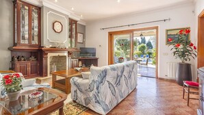 A spacious living room with a fireplace, a sofa, a television, and a dining area with chairs.