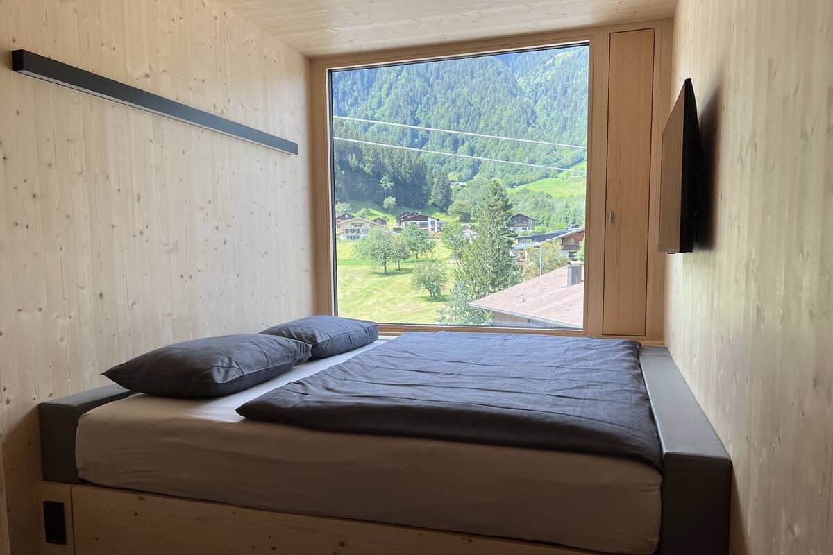 Une chambre à coucher avec un lit, une fenêtre et une vue sur un paysage verdoyant.