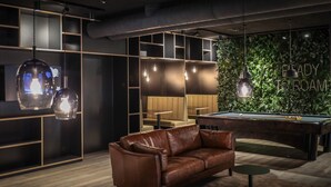 Een moderne lounge met een pooltafel, een leren bank en sfeerverlichting.