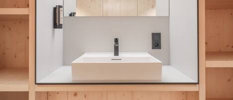 A modern bathroom with a central sink, a large mirror, and wooden paneling on the walls.