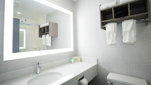 A modern bathroom with a large mirror, a sink, a toilet, and a towel rack. - Commack Inn (Commack)