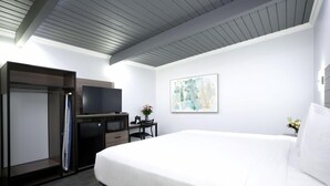 A hotel room with a bed, a desk, a television, and a wardrobe. - Commack Inn (Commack)