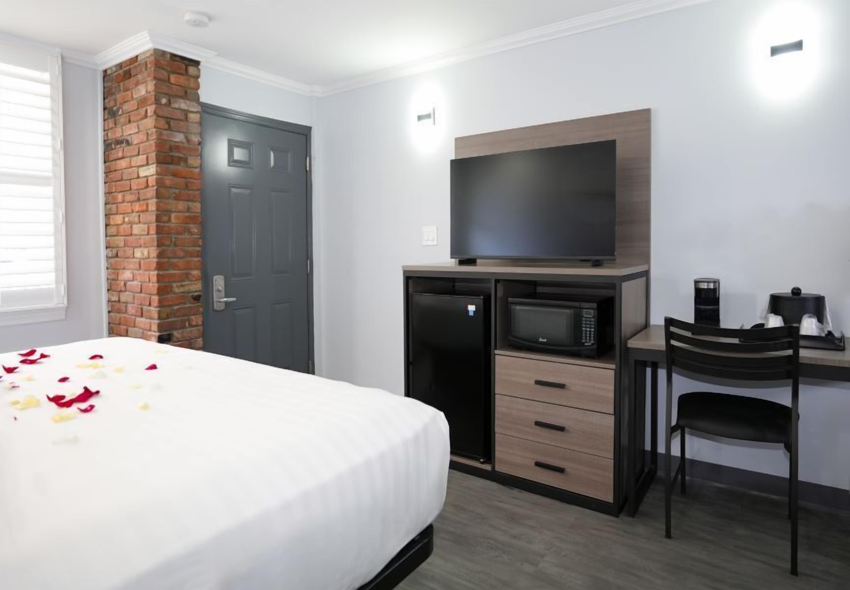 A hotel room with a bed, a desk, a microwave, and a television.