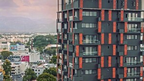 A modern high-rise building with a unique facade featuring a pattern of red and black panels.