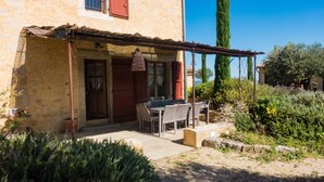 Un bâtiment en pierre doté d’un patio comprenant une table et des chaises.