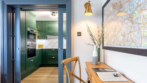 A kitchen with green cabinets, a wooden dining table, and a map on the wall.