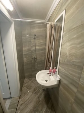 A bathroom with a shower, a sink, and a mirror. - Clock Apartments (Sveti Vlas)