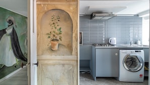 A compact kitchen with a washing machine, a tiled backsplash, and a painting on the wall. - Attico San Marco Top Floor Art 70 mq (Venice)