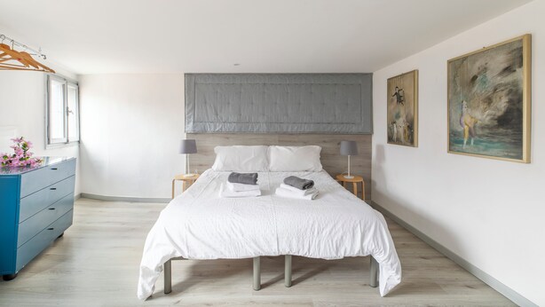 A modern bedroom with a large bed, bedside tables, a wardrobe, and artwork on the walls. - Attico San Marco Top Floor Art 70 mq (Venice)