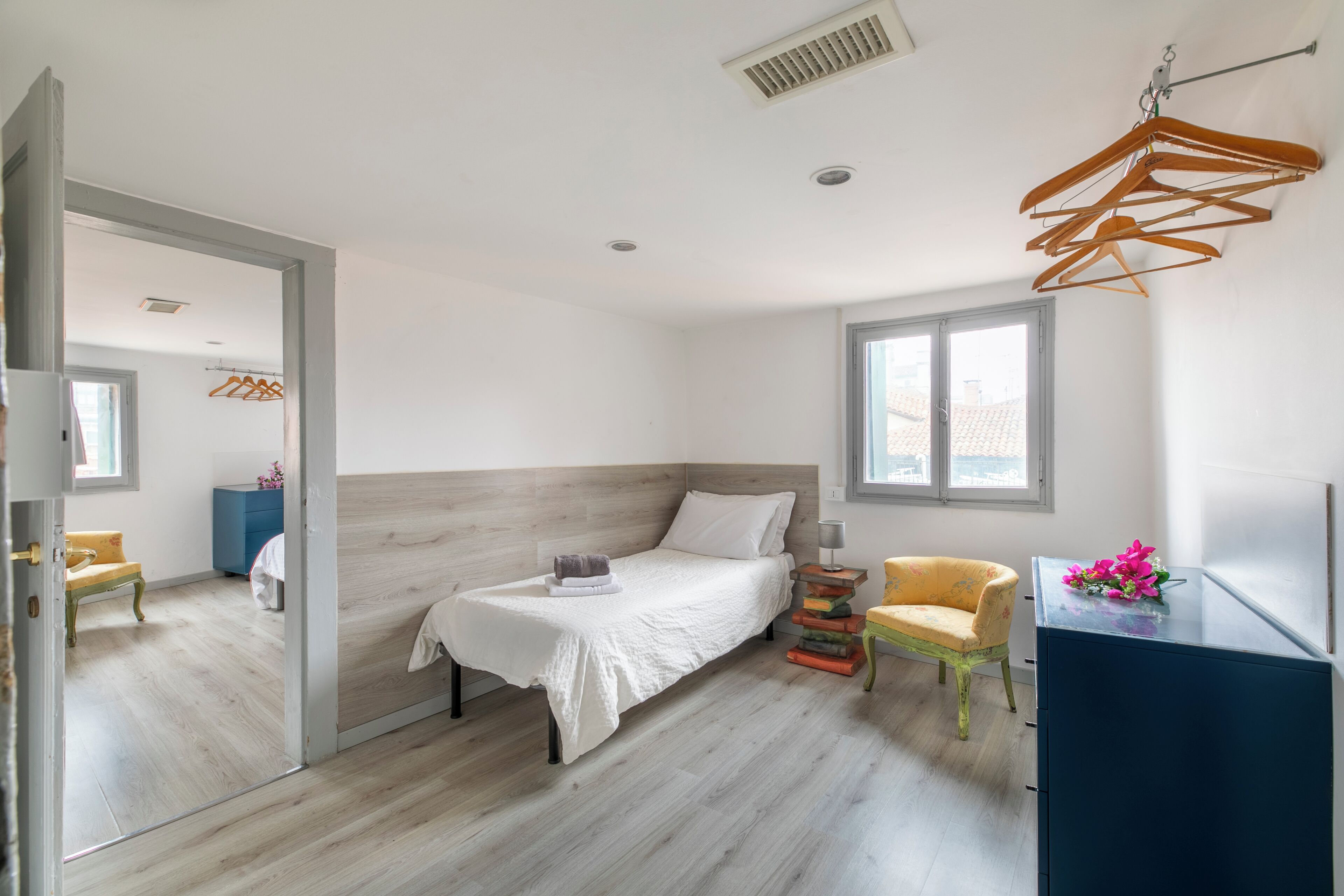 Une chambre à coucher avec un lit, une chaise, une commode et un miroir.