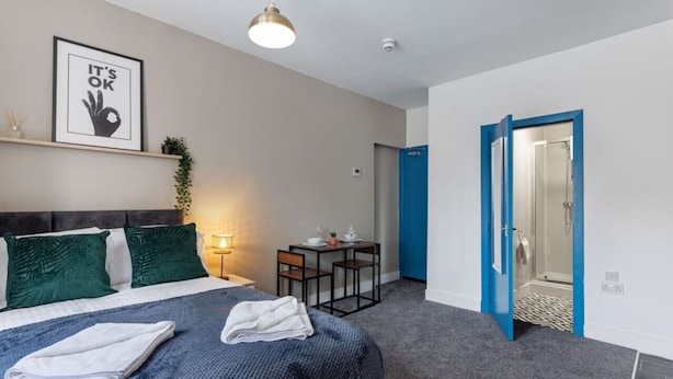 Ein modernes Hotelzimmer mit einem großen Bett, einem Schreibtisch und einer Duschkabine.