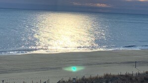 A beach with a fence in the foreground and a cloudy sky above. - Direct Beachfront with pool (Ocean City)