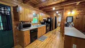 Una cocina compacta con armarios de madera, un microondas, un lavamanos y un refrigerador.