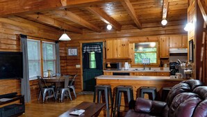 Interior de una cabaña de madera con comedor, cocina y sala de estar.