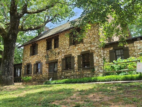 A stone building with a rustic appearance, featuring multiple windows and a sign indicating it is open.