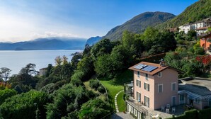 Une maison dotée d’un toit recouvert de panneaux solaires, entourée d’une végétation luxuriante et offrant une vue sur un lac.