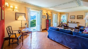 Un salon spacieux avec un grand canapé bleu, une chaise en bois et une table sur laquelle se trouvent une lampe et un vase.