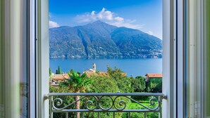 Un balcon doté d’une balustrade en métal, donnant sur un lac et des montagnes.