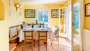 A dining area with a table set for four, a bench, and a view of the sea through large windows.