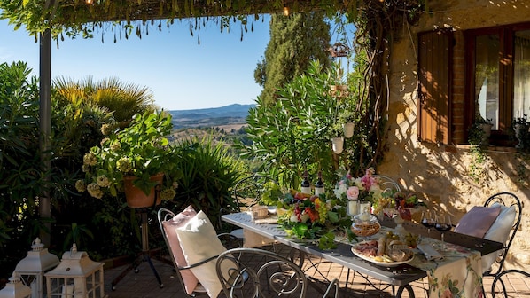 Eine Terrasse mit Essplatz, umgeben von Blumentöpfen und Blick auf die Landschaft.