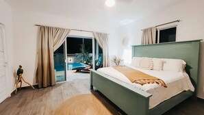 A bedroom with a bed, a view of an outdoor swimming pool, and a sliding glass door. - Beach Rental - Pet Friendly (chabihau)