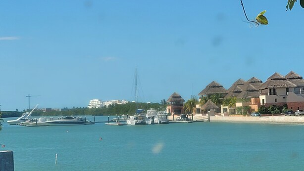 A marina with boats, a beach, and overwater bungalows with thatched roofs. - Beach Rental - Pet Friendly (chabihau)
