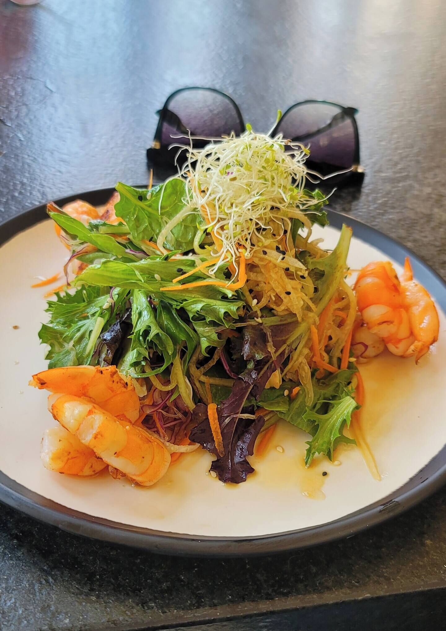 A plate of food with shrimp, greens, and sprouts.