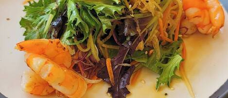 A plate of food with shrimp, greens, and sprouts.