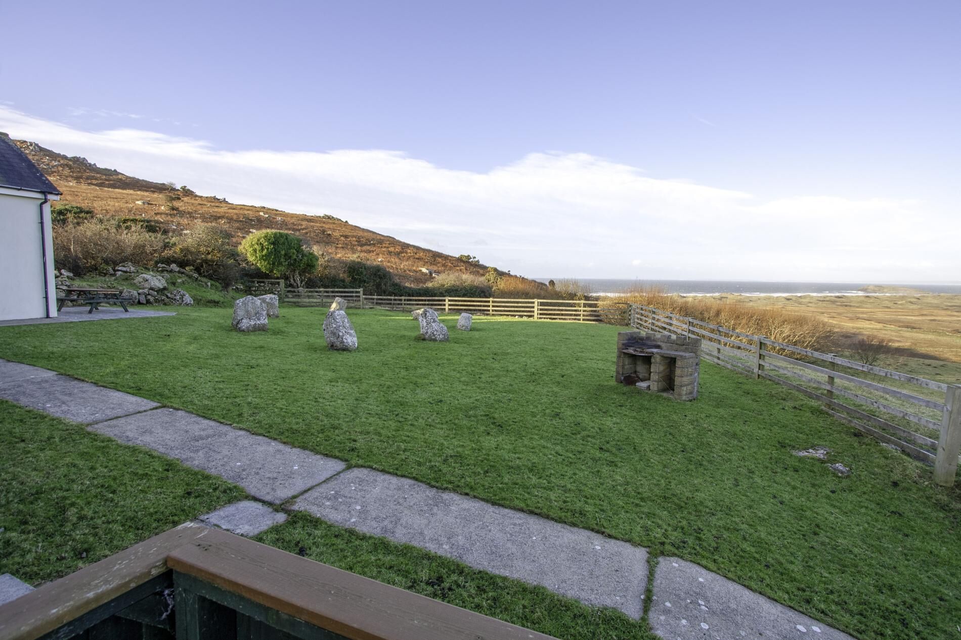 A grassy area with a stone bench and a wooden fence.