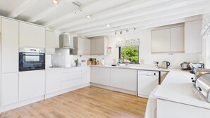 Una cucina moderna con mobili bianchi, forno integrato, cappa aspirante in acciaio inossidabile e una finestra vista verde.