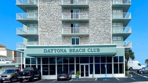 En byggnad med skylten ”Daytona Beach Club” på framsidan. Den har flera balkonger och en fasad av sten.