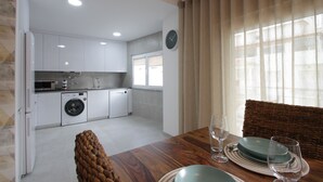 A modern kitchen with white cabinets, a washing machine, and a dining area with a table set for two.