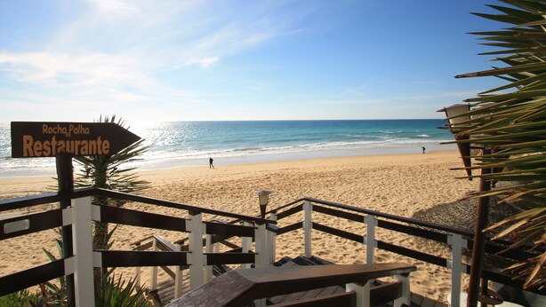 A beach with a sign for 'Rocha Palha Restaurante'.