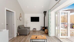 Un salon moderne comprenant un canapé, une table basse, une cheminée et une porte-fenêtre coulissante donnant sur un espace extérieur.