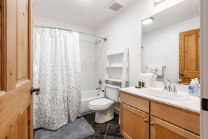 Ein Badezimmer mit Dusche, Toilette, Waschbecken und Holzschränken.