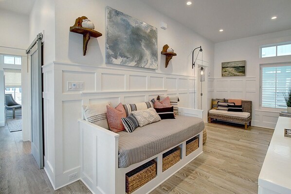A modern living room with a built-in bench, a large abstract painting, and a wicker sofa. - Beachful Easy Feeling 117 CE (Port Aransas)