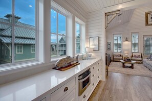A spacious kitchen with large windows, a dining area with a round table, and a cozy seating area with a sofa and chairs. - Beachful Easy Feeling 117 CE (Port Aransas)