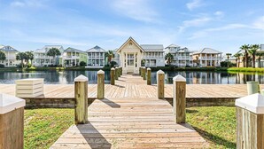 Un muelle de madera que conduce a una hilera de casas de playa, con un lago al fondo.