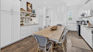 Una cocina moderna con armarios blancos, una mesa de comedor de madera y sillas de mimbre.