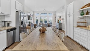 Una cocina moderna con armarios blancos, electrodomésticos de acero inoxidable y una amplia mesa de comedor de madera.