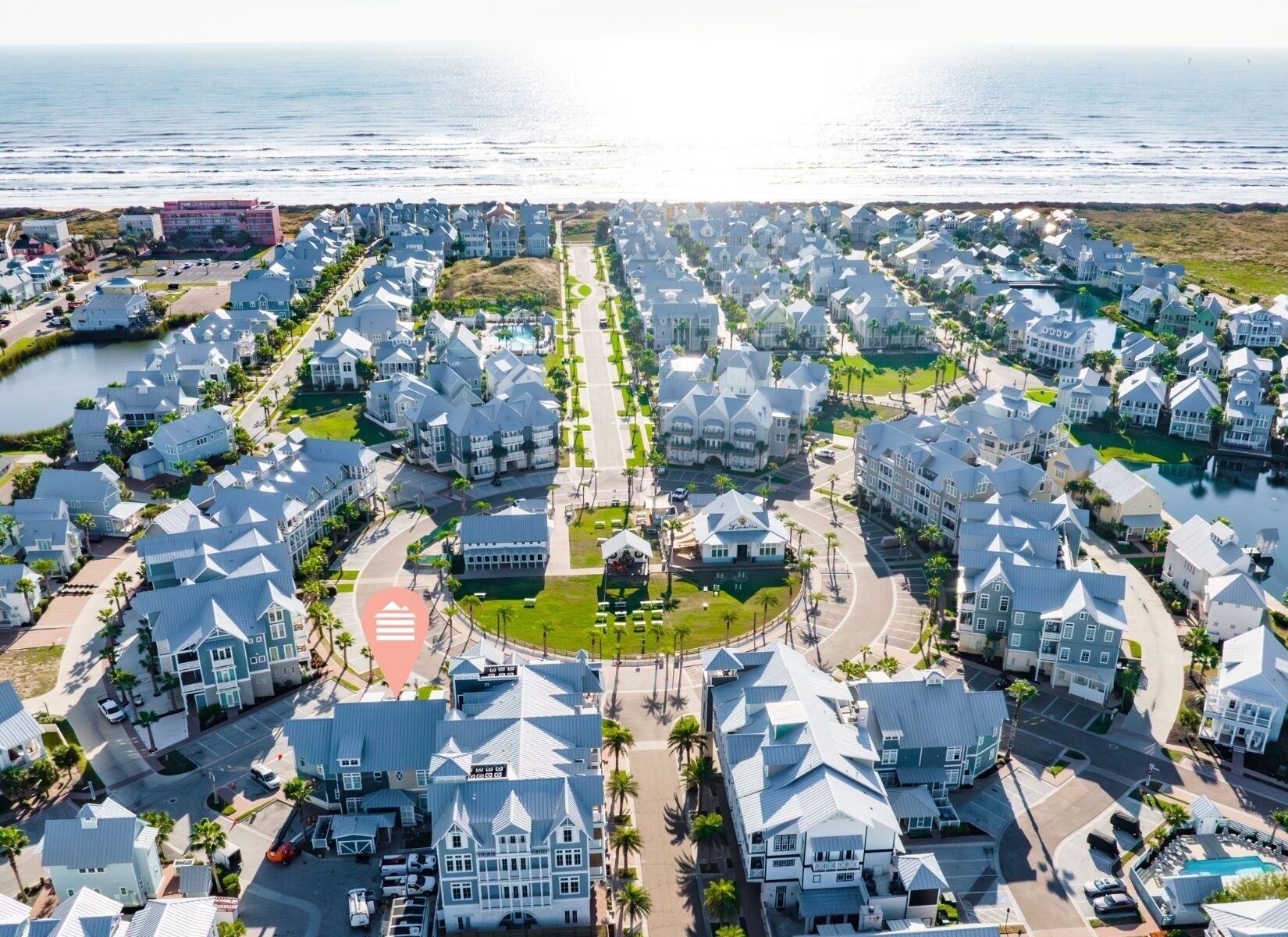 Un quartier résidentiel situé sur la côte, caractérisé par des maisons aux architectures similaires, une rue principale et une étendue d'eau en arrière-plan.