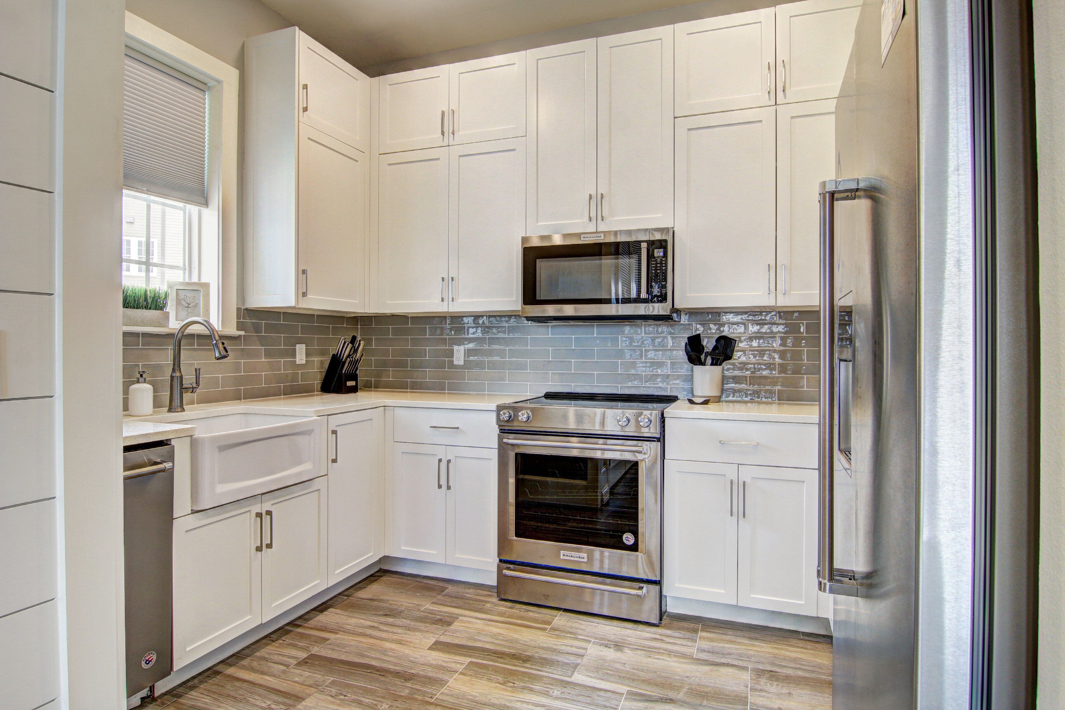 A modern kitchen with white cabinetry, stainless steel appliances, and a tiled backsplash.