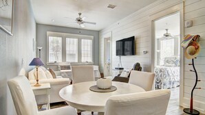 A dining area with a round table, white chairs, and a ceiling fan. - Beach Zen TC 10104 (Port Aransas)