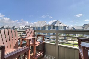 A balcony with wooden Adirondack chairs and a view of coastal houses. - C View TC 1310 (Port Aransas)
